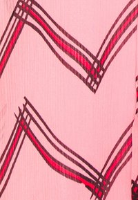 Tessuto rosa chiaro con un motivo di ondulati strisce nere e rosse. La trama appare leggermente sgualcita, aggiungendo profondità al design.