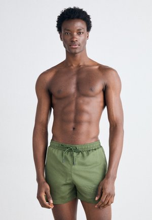 Shorts de bain verts en tissu léger, dotés d'une taille élastique avec cordon de serrage, et d'un détail logo discret à l'avant.