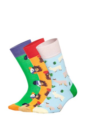 Drie kleurrijke sokken met patronen van honden, beren en lama's op groene, oranje en lichtblauwe achtergronden, elk met contrasterende boordjes en tenen.