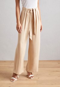 Beige broek met wijde pijpen, een hoge tailleband, voorplooien en een bindceintuur. Gemaakt van een gladde stof, met een ontspannen silhouet.
