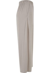 Pantalon beige à taille élastique et jambes larges avec poches latérales, confectionné dans un tissu doux et fluide.