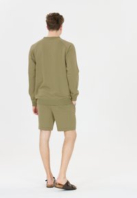 Olivgrön sweatshirt med ribbade manschetter, i kombination med matchande shorts. Designen har en avslappnad passform och en bakficka.