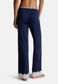 Navy blauwe loungebroeken met een vloeiend ontwerp, zijn voorzien van een kantafwerking aan de zoom, een soepele textuur en een elastische tailleband aan de achterkant.