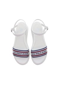 Bílé sandály s širokým textilním páskem s červenými, bílými a modrými pruhy a logem "U.S. POLO ASSN.", nastavitelným páskem kolem kotníku, hladkým povrchem.