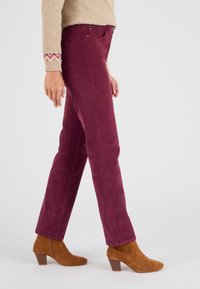 Bordeaux corduroy broek met een rechte pasvorm, voorzien van voorzakken en een gladde textuur, gecombineerd met tan kleurige suède enkellaarsjes.