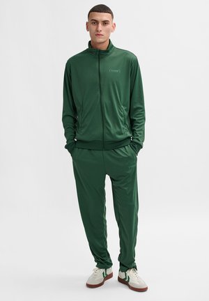 Green athletic tracksuit made of smooth, stretchy fabric; features a zip-up jacket and tapered pants with a subtle logo on the chest.