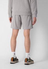 Sweatshirt gris et short assorti, en mélange de coton, avec une coupe décontractée. Détails notables : surface texturée, design avec bandes sur les côtés et baskets de sport.