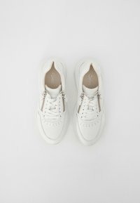 White sneakers with a textured upper, lace and zip closure, and perforated detailing. Rubber sole with a rounded shape.