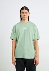 Bomulds T-shirt i lys grøn med korte ærmer og rund halsudskæring. Har et lille hvidt logo på brystet.