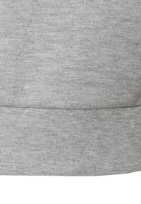 Hellgrauer Strickstoff mit sichtbarer Naht und geripptem Saum, vermutlich Teil eines Kleidungsstücks wie einem Pullover oder Sweatshirt.