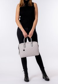 Grå quilted håndtaske med sølvdetaljer og dobbelthåndtag; har en lynlås og sidelomme; glat tekstur; rektangulær form.