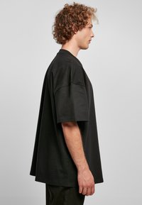 Zwarte oversized t-shirt met korte mouwen, gemaakt van soepele katoen. Heeft een losse pasvorm en een ronde halslijn. Eenvoudig ontwerp zonder patronen of accenten.