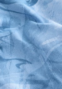 Tessuto blu chiaro con una superficie liscia, caratterizzato da un sottile motivo astratto. Il materiale appare morbido e leggermente elastico.