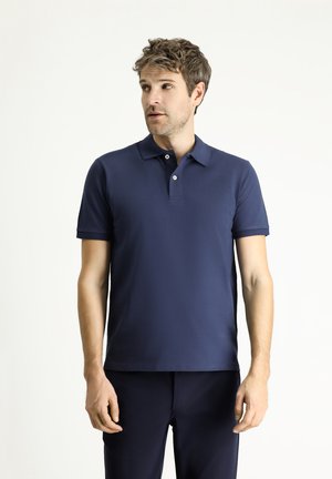 Polo azul marino fabricado en una suave mezcla de algodón; cuenta con mangas cortas, un cuello clásico y una tapeta de dos botones para el cierre.