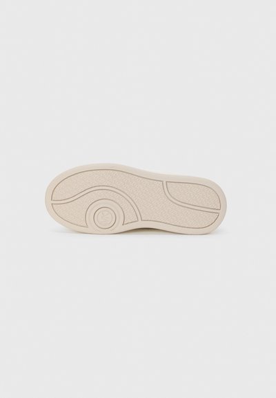 Skosåle i lys beige gummi, med en teksturert overflate med et sirkulært logo og buede designlinjer. Glatt og litt fleksibel.