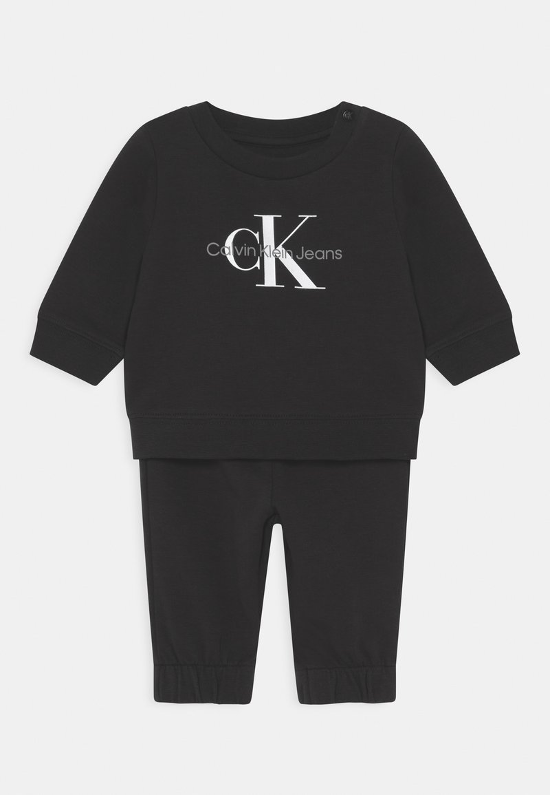 Zwart katoenen twee-delige set met een lange mouwen top met ronde hals en "CK" logo, gecombineerd met tapered broek met elastische boorden.