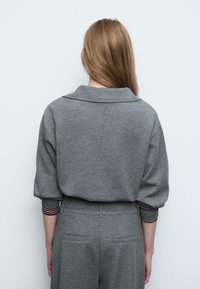 Grå sweatshirt med krave, afslappet pasform og manchetter med stribede detaljer. Glat tekstur og afslappet design.