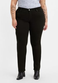 Svarta skinny jeans i denim med en slät yta. Har en klassisk femficksdesign och medelhög midja. Matchas med svarta ankelboots.