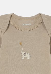 Body de algodón beige con un elefante impreso sosteniendo un globo dorado, con cuello redondo y mangas cortas.