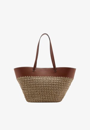 Grote tote tas met bruine leren bovenkant en handvatten, en een beige gevlochten stro onderkant, getoond tegen een witte achtergrond.