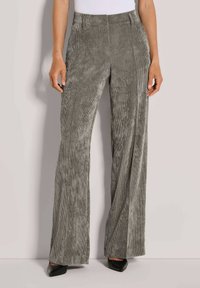 Graue Cord-Hosen mit weitem Bein und vertikalen Rippungen, hoher Taille und glatter Oberfläche, kombiniert mit spitzen schwarzen Absatzschuhen.