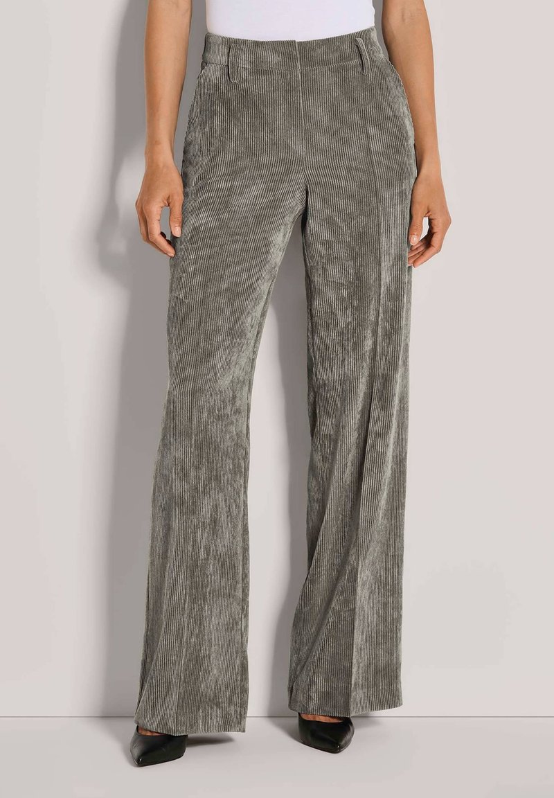 Graue Cord-Hosen mit weitem Bein und vertikalen Rippungen, hoher Taille und glatter Oberfläche, kombiniert mit spitzen schwarzen Absatzschuhen.