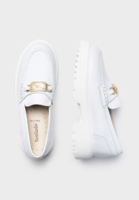 Mocassins blancs avec une finition brillante, détails en or sur la sangle, semelle épaisse blanche et coutures autour de la tige.