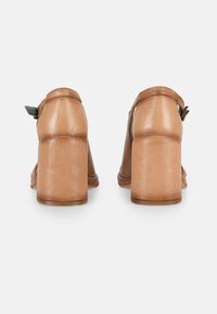 Brown leather heeled sandals with a chunky heel. Features an adjustable ankle strap and textured surface. Designed for comfort and stability.