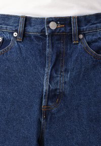 Jeans i denim med en mørkeblå vask, med kontrastsøm, metallknaplukning og klassisk fem-lomme-design.