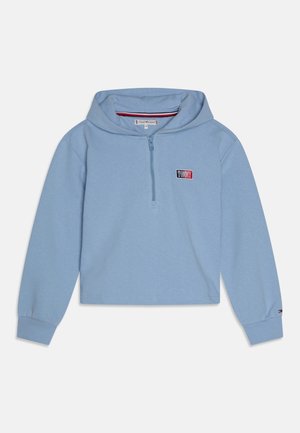 Hoodie court à manches longues bleu clair avec demi-fermeture éclair à l'avant, poignets côtelés et petite étiquette logo "Tommy" sur la poitrine et la manche.