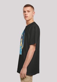 Black cotton t-shirt featuring a colorful graphic print on the front. The design includes stars and a blue silhouette. Short sleeves and loose fit.