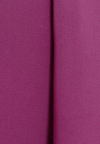 Gros plan d’un tissu magenta plié montrant une fine texture tissée et une légère ombre le long du pli.