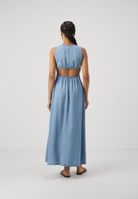 Rochie maxi din denim de culoare albastru, cu talie strânsă și spate descoperit. Confecționată dintr-un material moale și ușor, având un design simplu și fluid.