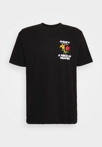 Černé bavlněné tričko s barevným květinovým vzorem v žluté a červené barvě na hrudi, s textem "OBEY worldwide" a "A PIECE OF HEAVEN".