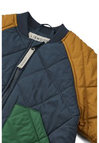 Quilted jacket featuring a navy body, mustard sleeves, and a green accent. Material is smooth with a ribbed collar and a zipper closure.