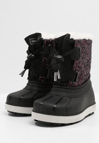 Czarne i purpurowe zimowe buty z gumową podeszwą, materiałową górą, grubymi sznurówkami i białym futerkiem widocznym na górnych krawędziach.