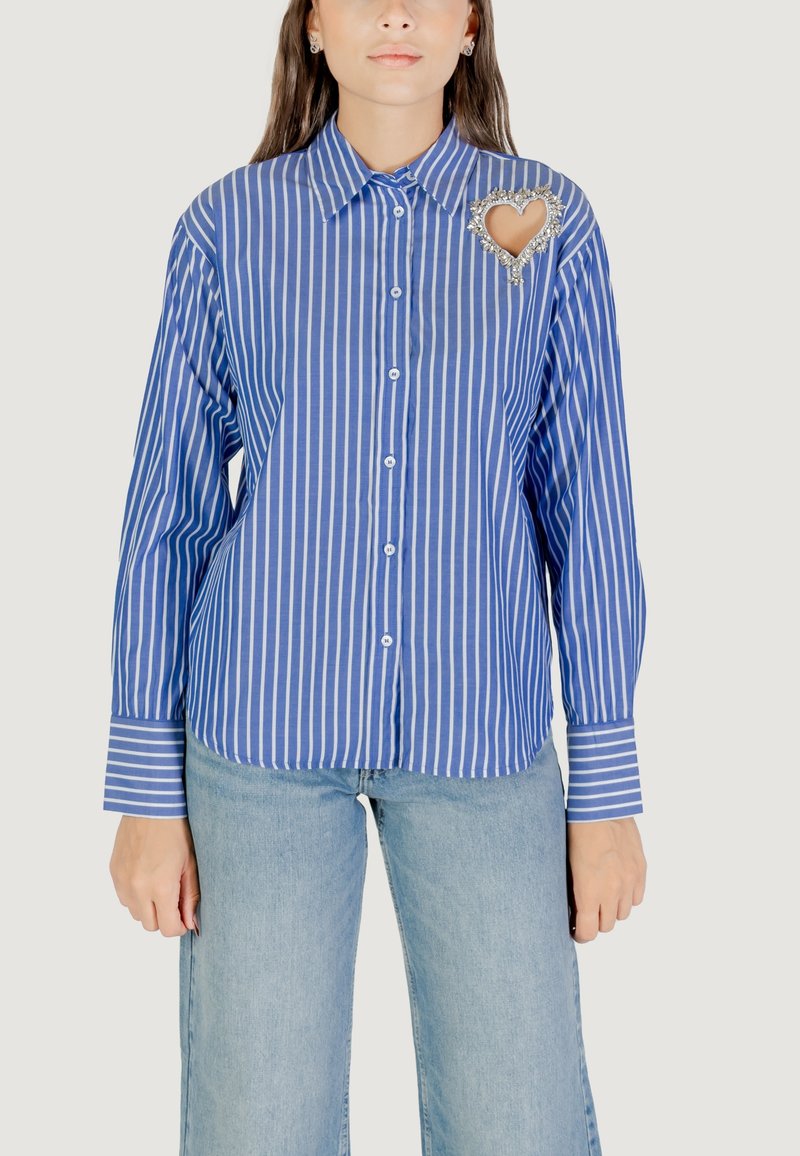 Camisa de manga larga a rayas azul y blanca con botón en el frente, que presenta un adorno en forma de corazón en el pecho y mangas con puños.