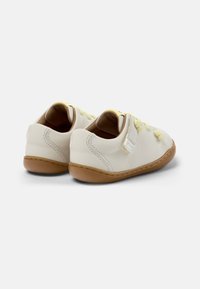 Scarpe di pelle color crema con lacci gialli, forma arrotondata e suola in gomma marrone. Presentano cuciture e una piccola etichetta del marchio.