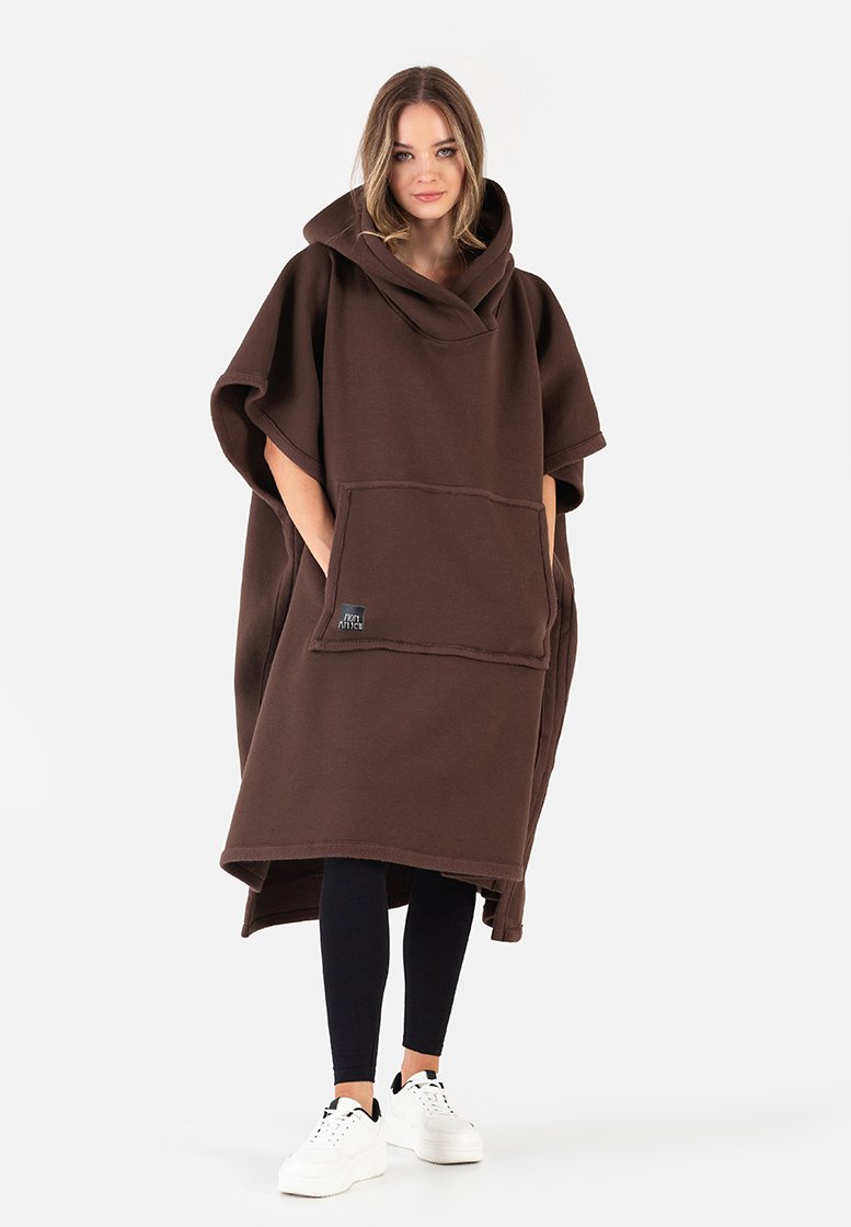 Brązowy polarowy poncho z kapturem, dużą przednią kieszenią i luźnym krojem. Posiada szerokie rękawy oraz miękką teksturę. Noszone na czarnych legginsach.