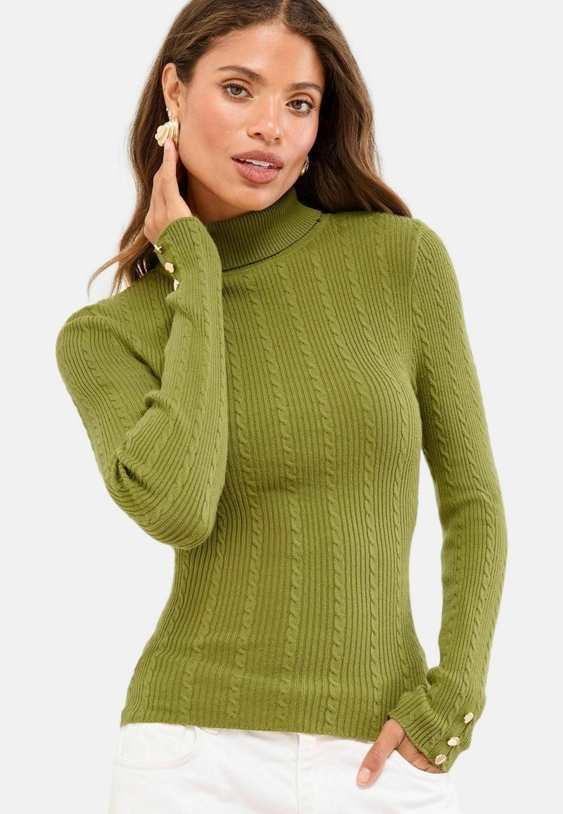 Oliivinvihreä joustokuosisella turtleneck-neuleella, jotka ovat muotoilultaan yksinkertaisia ja joissa on kolme nappia hihansuissa.