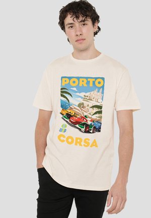 Young man wearing a white T-shirt with a colorful Porto Corsa racing cars graphic and black pants, standing against a plain background.