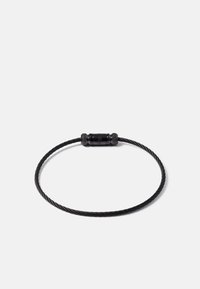 Pulseira de fio metálico preto com um fecho cilíndrico liso. Apresenta uma textura torcida, design leve e uma aparência minimalista.