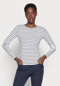 Långärmad T-shirt med marinblå ränder på vit bakgrund, rund halsringning, med en liten hjärtlogotyp på vänster bröst.