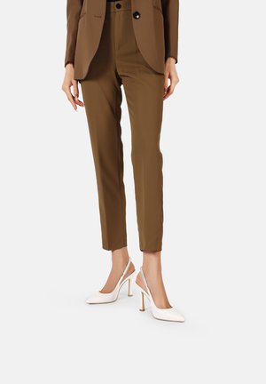 Blazer marrone su misura, pantaloni attillati coordinati e décolleté bianchi con finitura testurizzata. Design di tacchi alti notevole e linee pulite.