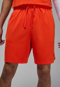Herre treningsshorts, lys oransje, laget av lett mesh-stoff. Har elastisk midjebånd med snøring og små logo-detaljer.