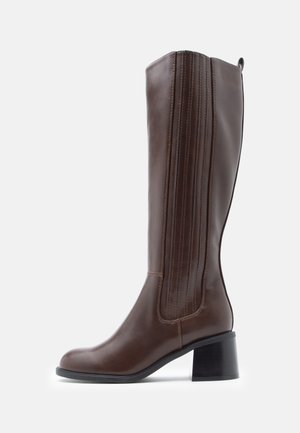 Brown leather knee-high boot with a rounded toe, vertical stitching detail, and a block heel. Smooth texture with a polished finish.