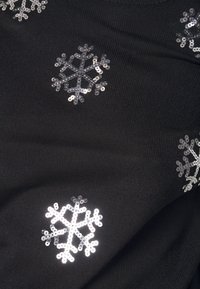 Zwarte gebreide stof met zilveren pailletten sneeuwvlokontwerpen verspreid over het oppervlak, wat textuur en een feestelijk detail toevoegt.