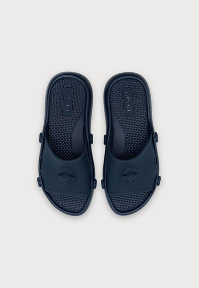 Paire de sandales slides noires Versace avec semelles texturées et logos tête de Méduse sur les brides, vues de dessus sur fond blanc.