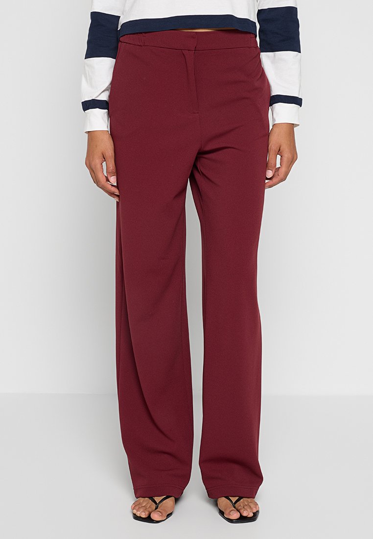 Bordeaux brede broek van soepel materiaal met een getailleerde pasvorm en een voorplooidesign. Geklopt met een top met marine accenten.