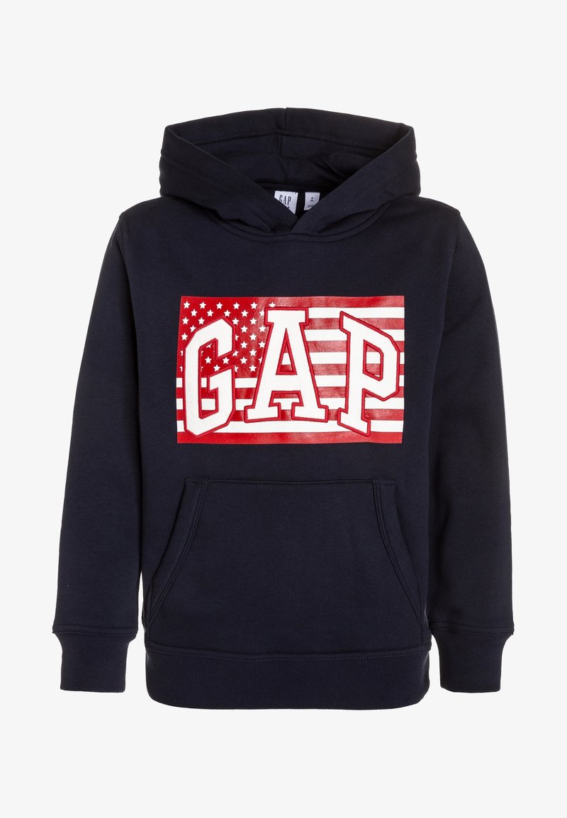 Sweat à capuche bleu marine avec poche avant et motif rouge et blanc comprenant le texte "GAP" sur un fond stylisé de drapeau américain.